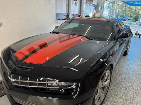 Black Camaro with red racing stripes after paint correction and ceramic coating
